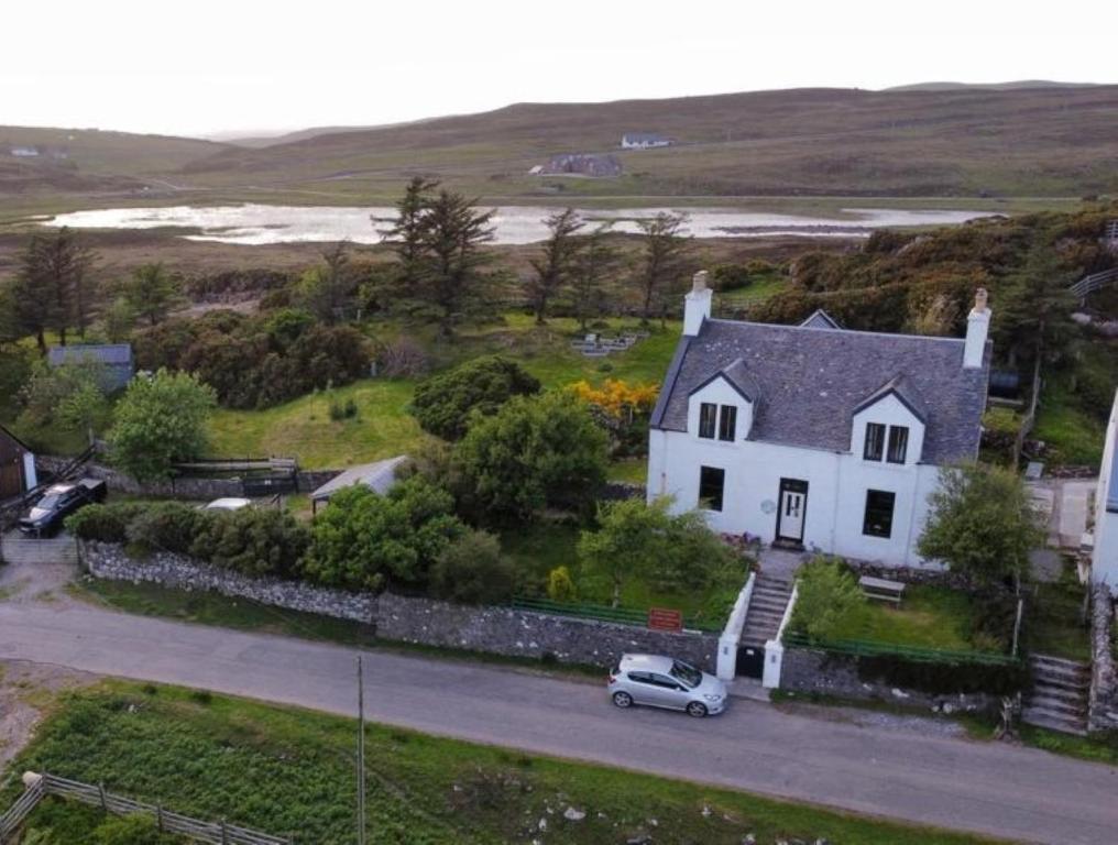 a white house with a car parked in front of it at Cruachan Guest House in Stoer