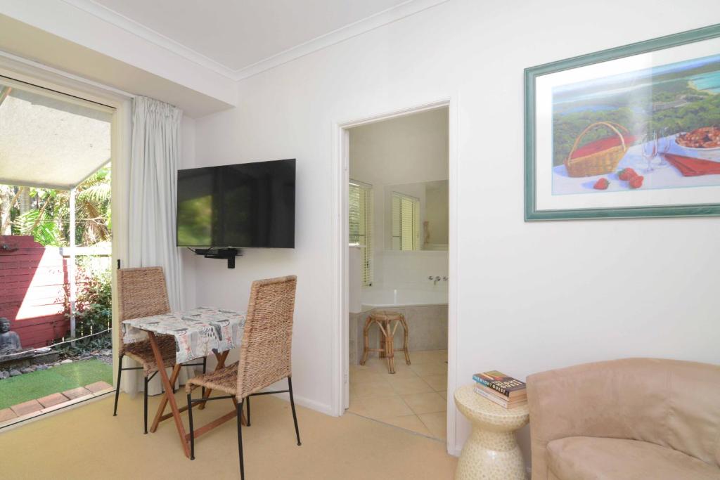 un soggiorno con tavolo, sedie e TV di Howie's Place Noosa a Noosaville