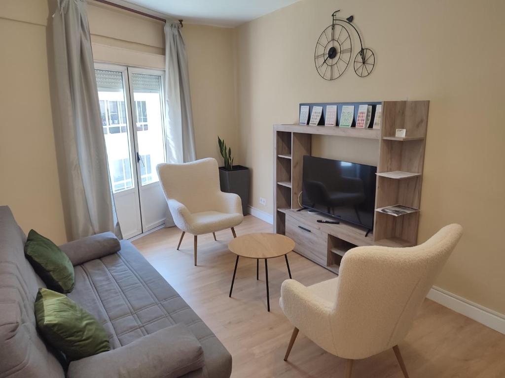 ein Wohnzimmer mit einem Sofa, Stühlen und einem TV in der Unterkunft VUT La Villa in Vilagarcia de Arousa