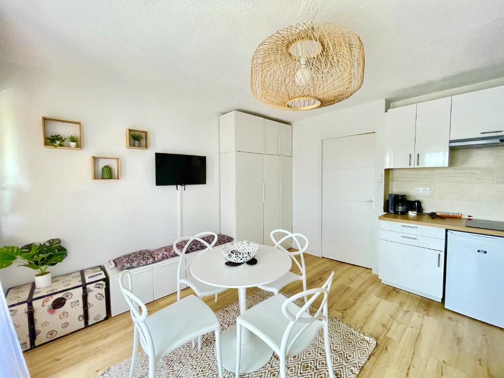 eine Küche und ein Wohnzimmer mit einem weißen Tisch und Stühlen in der Unterkunft Caporizon-Baillenia-T1 Vue Montagne - Piscine St Jean de luz in Saint-Jean-de-Luz