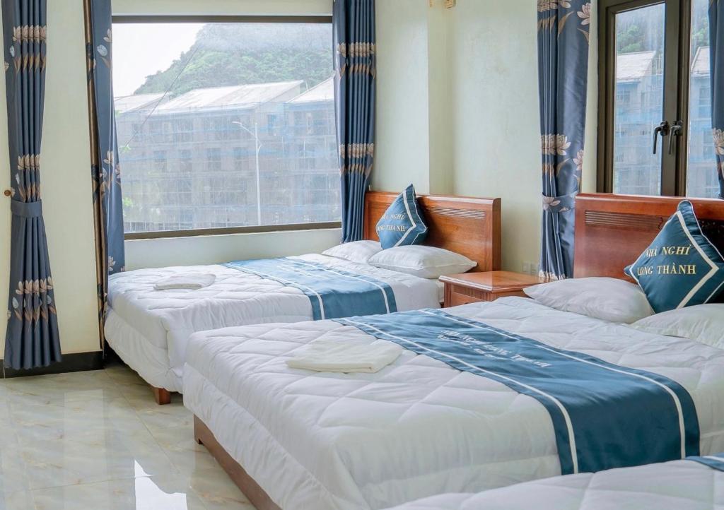 a hotel room with three beds and a window at Long Thành Motel in Cat Ba