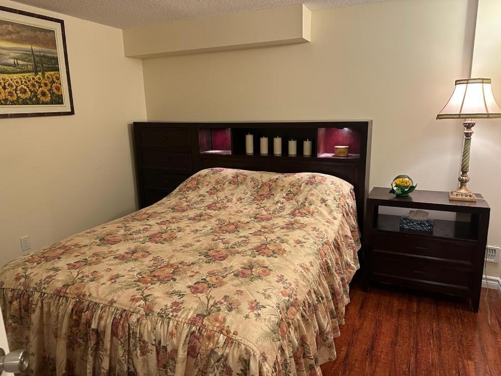 列治文山的住宿－Basement apartment，一间卧室配有一张床和一张带台灯的桌子
