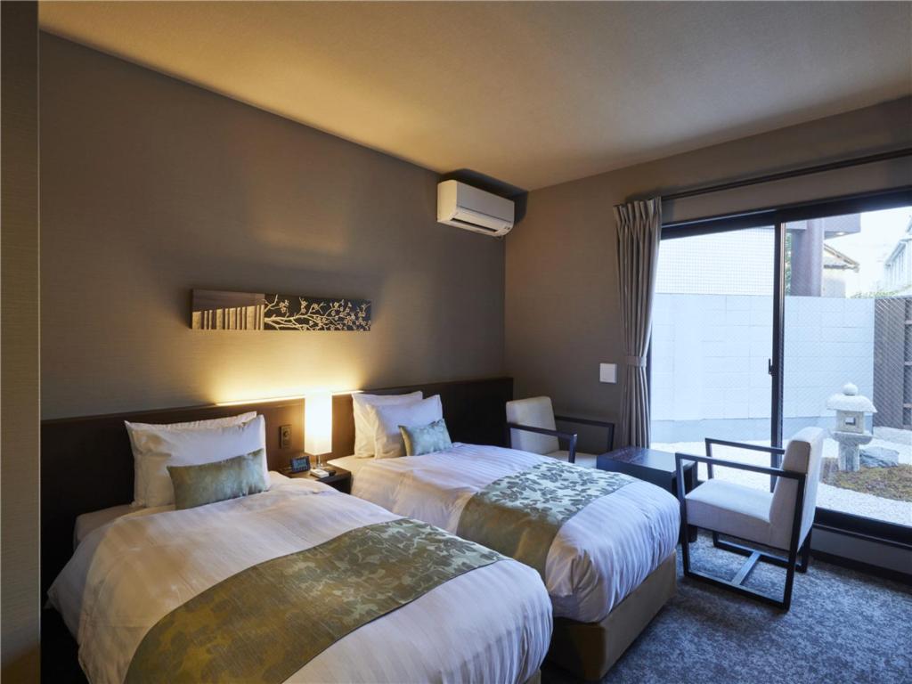 京都市にある若平安白川ホテル　Waka Heian Shirakawa Hotelのベッド2台と窓が備わるホテルルームです。