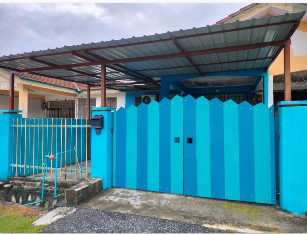 ein blauer Zaun vor einem Haus mit einem Dach in der Unterkunft Blue Homestay Teluk Kemang Port Dickson in Port Dickson