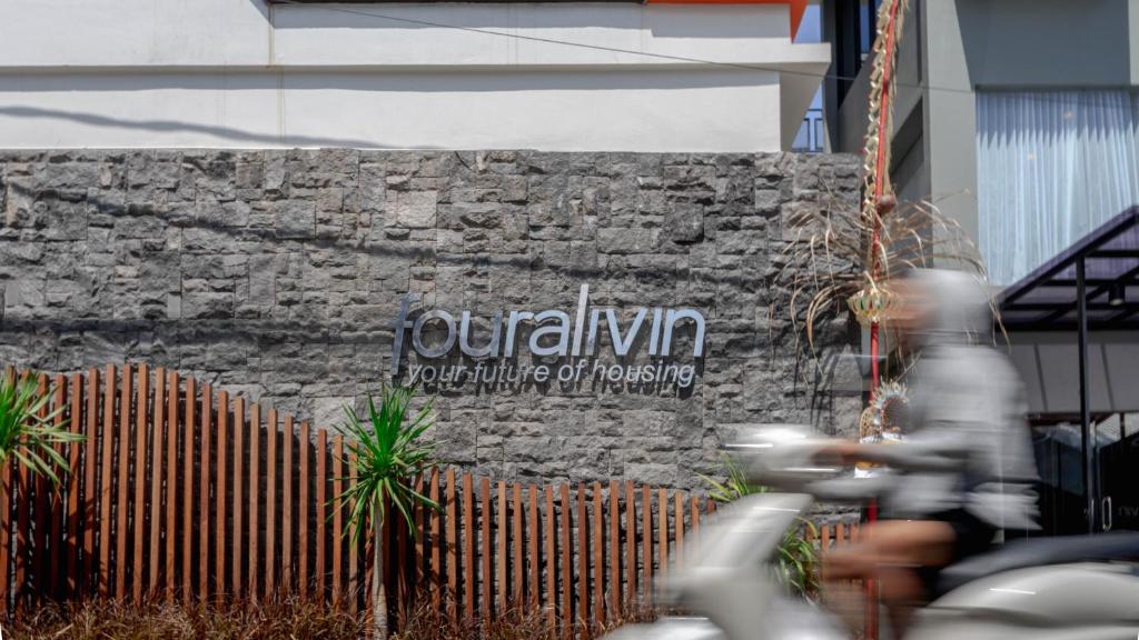 a person riding a bike in front of a sign at Fouralivin in Kesiman