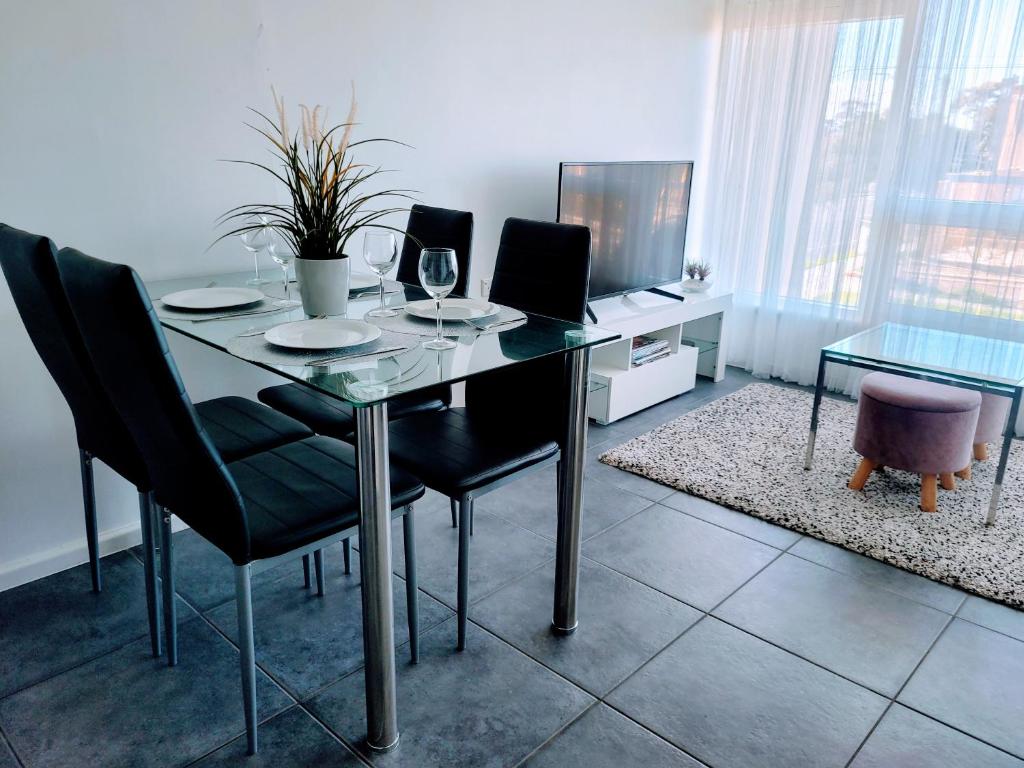uma sala de jantar com uma mesa de vidro e cadeiras em Zig Zag at Henley ~ BEACH ~ DINING ~ WiFi ~Airport em Henley Beach South