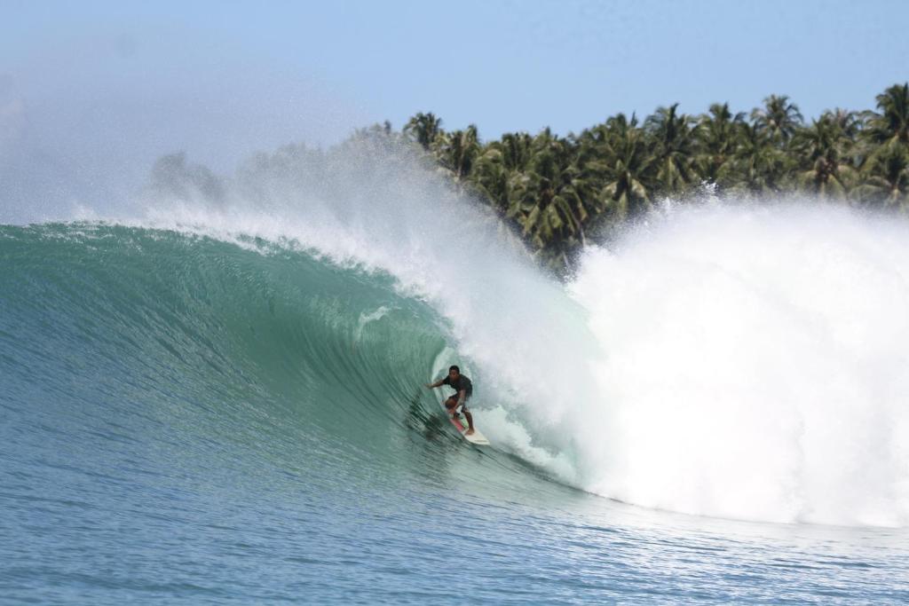 Un uomo che cavalca un'onda su una tavola da surf nell'oceano di Jimmy Losmen Nias a Lagudri