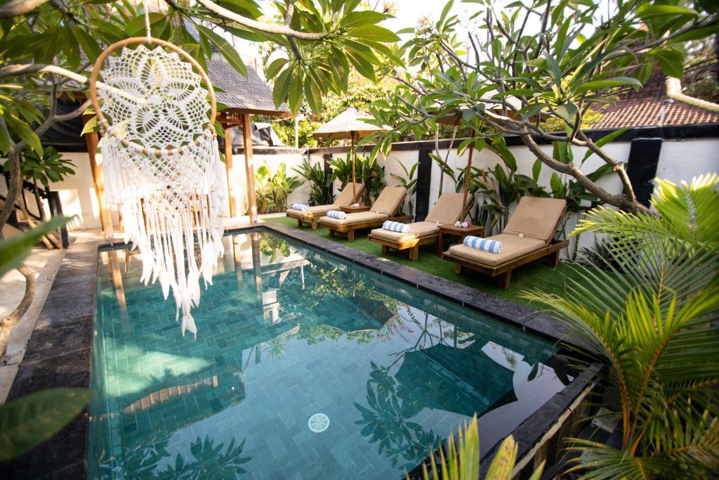 een zwembad met stoelen en een hangmat naast een huis bij Rumah Singa - Holistic Healing Retreat in Gili Air