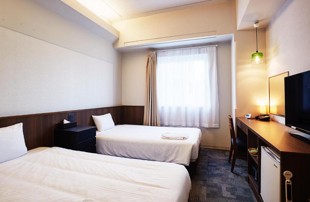 pokój hotelowy z 2 łóżkami i telewizorem w obiekcie RJ Hotel Naha w mieście Naha