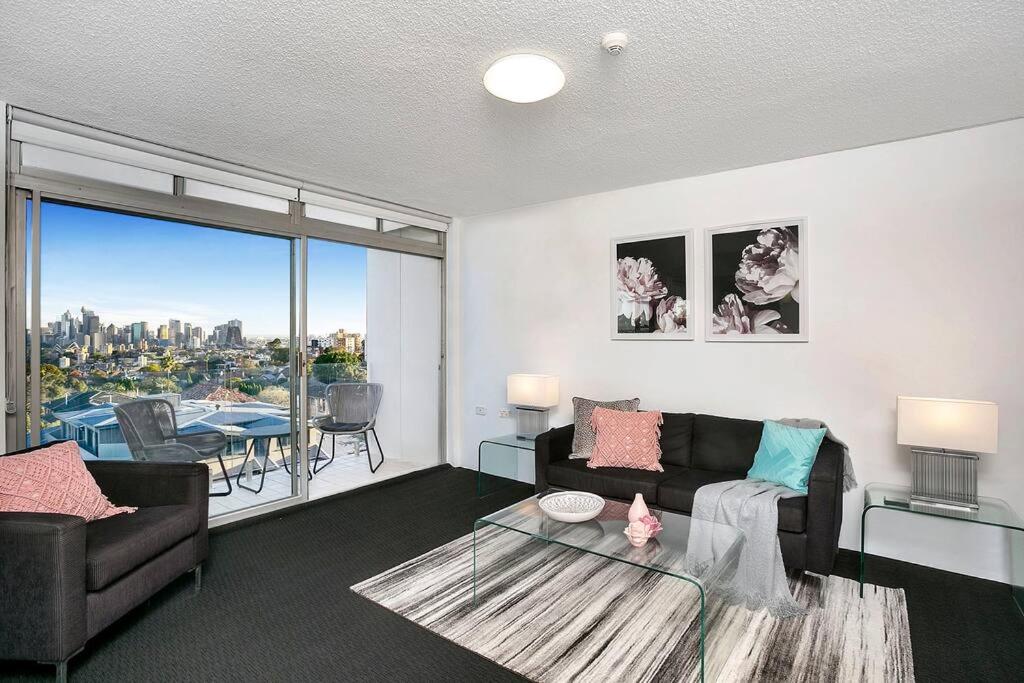 a living room with a couch and a view of the city at HARIS - Modern 2BR Apartment with Views in Sydney