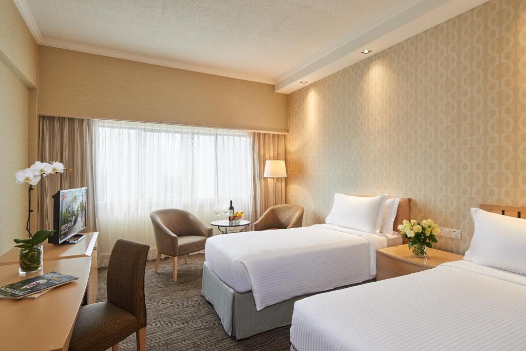 シンガポールにあるYork Hotelのベッド2台、椅子、テーブルが備わるホテルルームです。