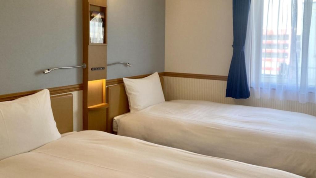 函館市にある東横INN函館駅前大門のベッドが2つと窓があるホテルの部屋
