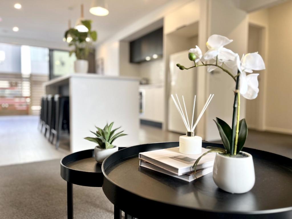 a black table with white flowers and books on it at Modern & Central City in Hamilton