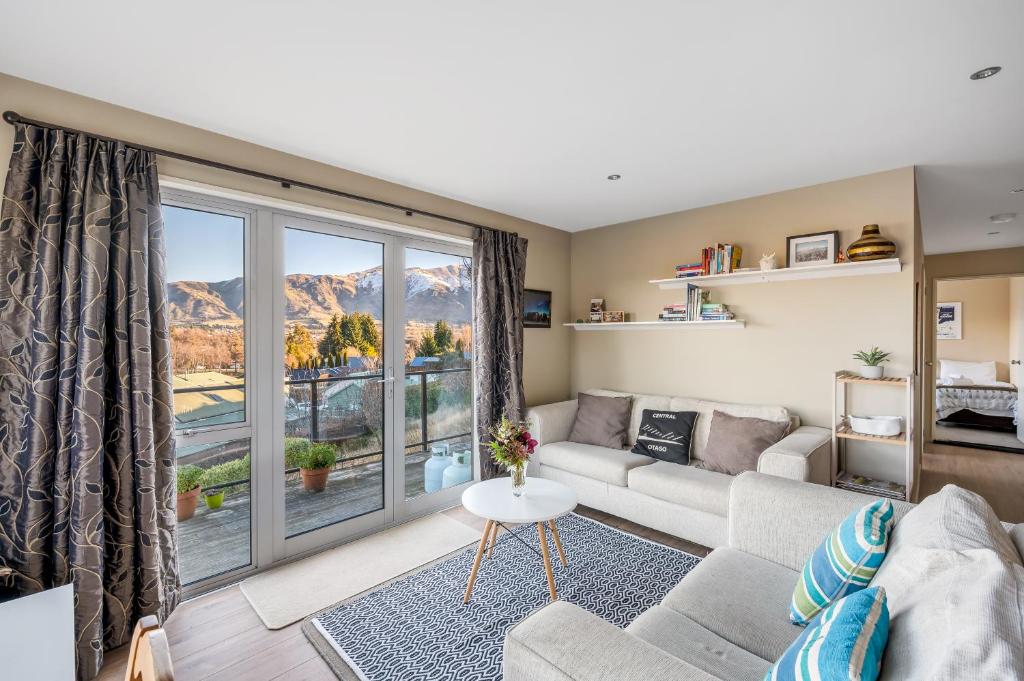 a living room with a couch and a large window at Criffel Garden Apartment in Wanaka
