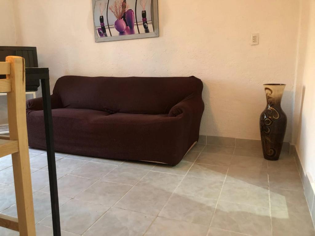 Sofá marrón en la sala de estar con jarrón en La Fortaleza, en Tonatico