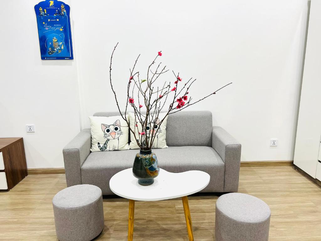 - un salon avec un canapé et un vase sur une table dans l'établissement Studio Luxury Sakura - Vinhome Smart city Mỹ Đình, à Hanoï
