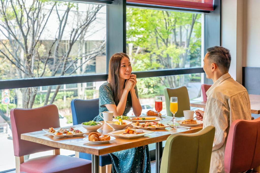 a man and a woman sitting at a table with food at Hotel Nikko Kanazawa in Kanazawa