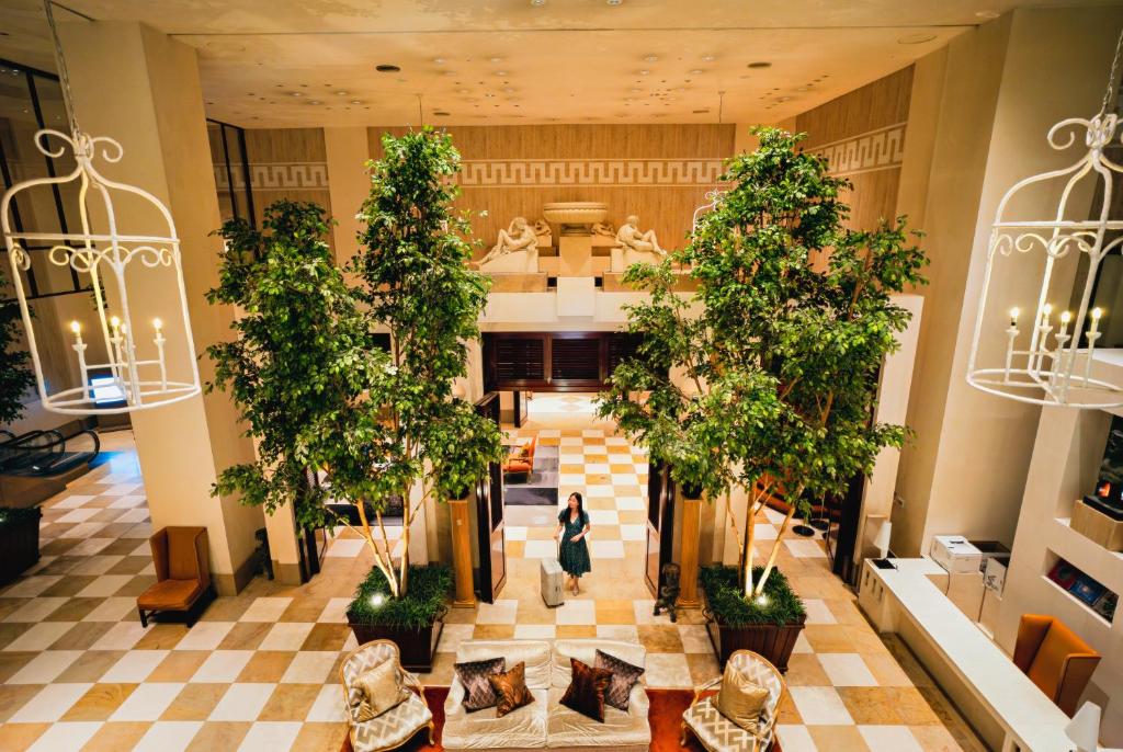a woman walks through the lobby of a building with trees at Hotel Nikko Kanazawa in Kanazawa