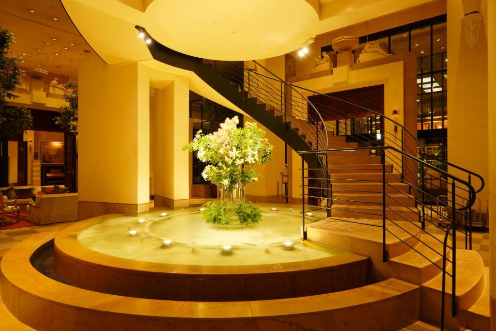 a lobby with a staircase and a vase of flowers at Hotel Nikko Kanazawa in Kanazawa