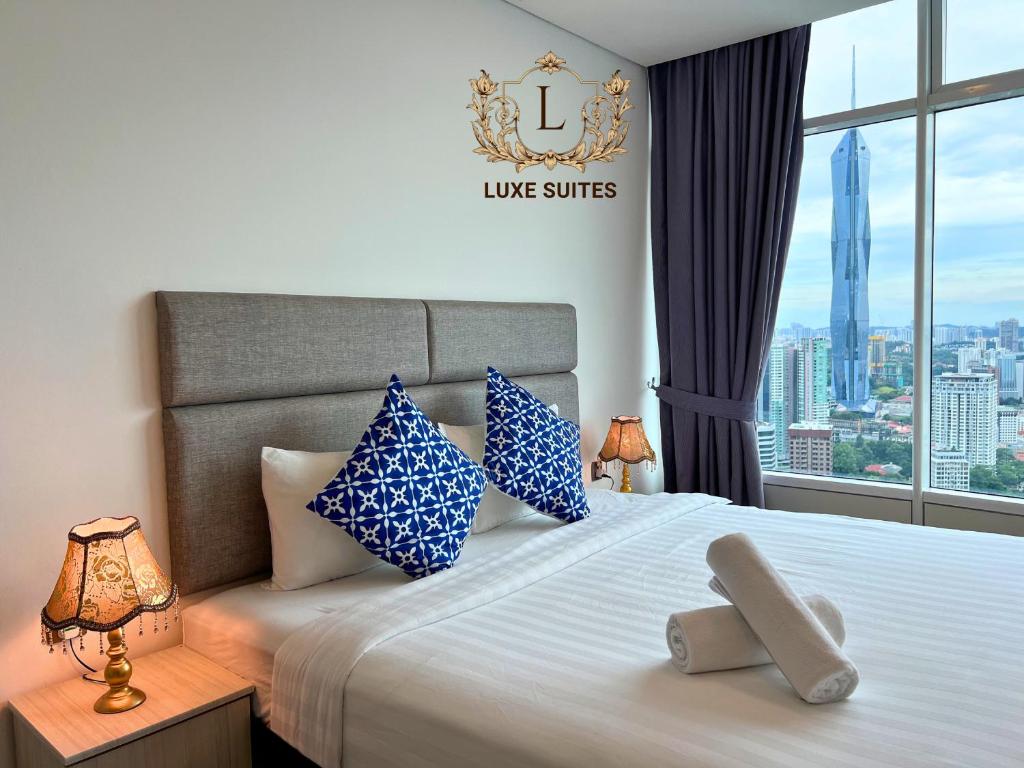 a bedroom with a large bed with blue and white pillows at Luxe Suites at Vortex KLCC in Kuala Lumpur