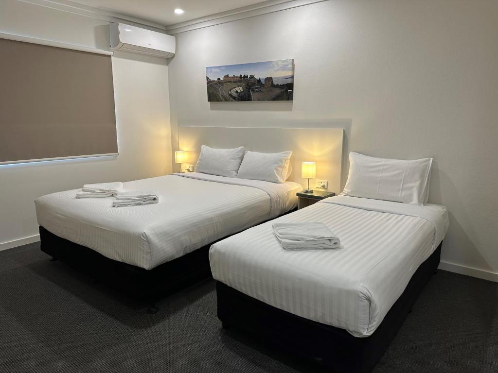 2 Betten in einem Hotelzimmer mit weißer Bettwäsche in der Unterkunft Golf View Motel in Sanctuary Point
