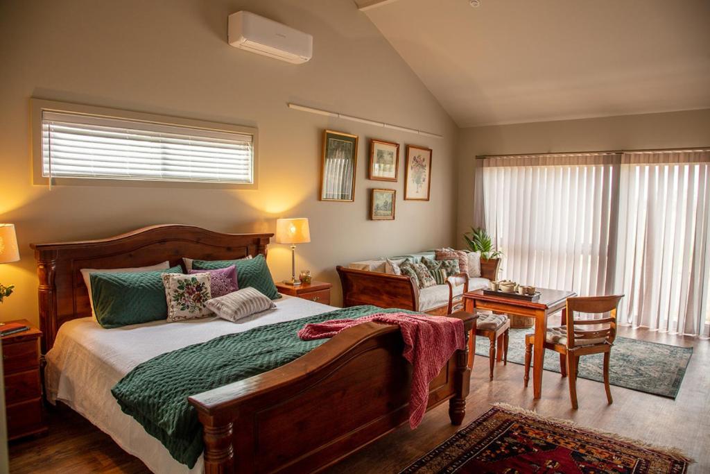 a bedroom with a bed and a table and a chair at Meander Retreat - The Green Room in Springton
