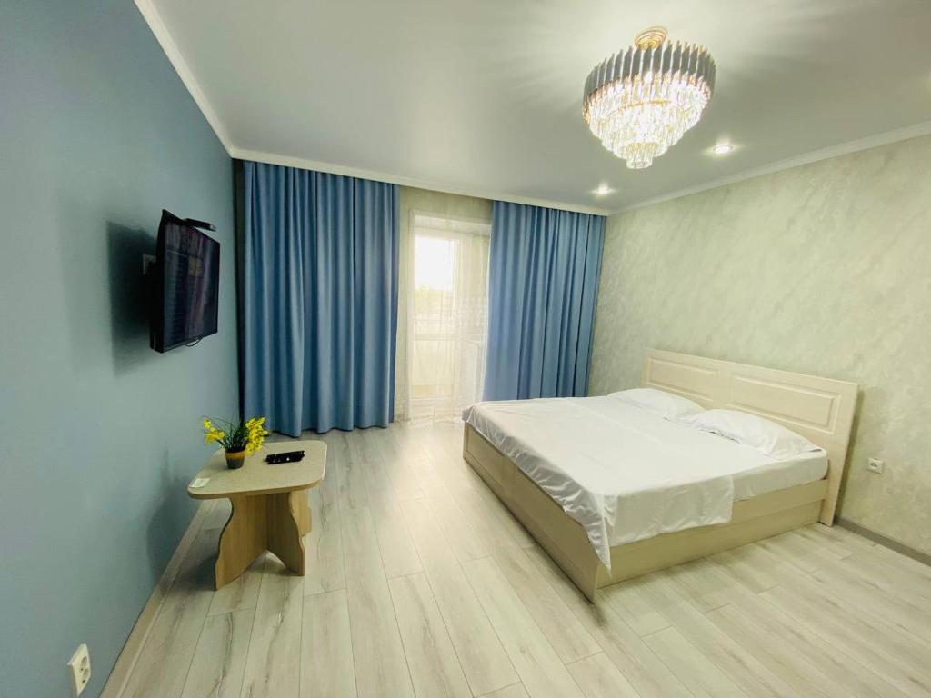 1 dormitorio con cama, mesa y lámpara de araña en 2.х полноценная . ЖК комфорт. en Kokshetau
