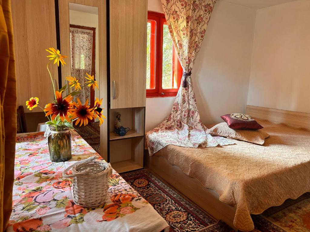 a bedroom with a bed and a window with flowers at Căsuța Dede in Buzău