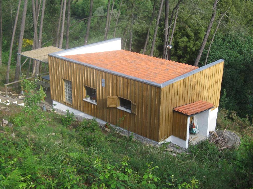una pequeña casa con techo naranja en un bosque en Casa Do Pinheiral, en Ponte da Barca