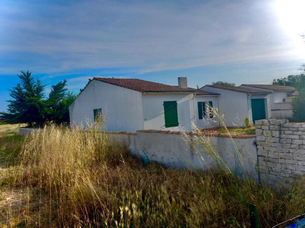 une maison blanche avec des portes vertes dans un champ dans l'établissement Maison sainte marie de ré, à Sainte-Marie de Ré
