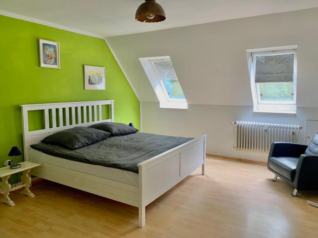 a bedroom with green walls and a bed and a chair at Wohnen am Wasserschloss Sandizell in Schrobenhausen