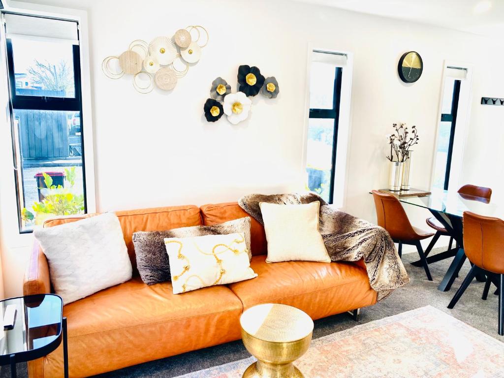 a living room with an orange couch with pillows at Walk to CHCH CBD modern townhouse 2 bed 2 baths in Christchurch