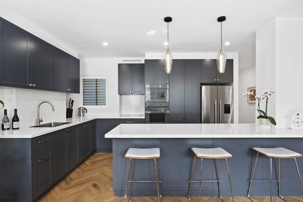 a kitchen with black cabinets and a blue island with stools at Potts Point l 2 Bedroom Stylish Retreat in Sydney