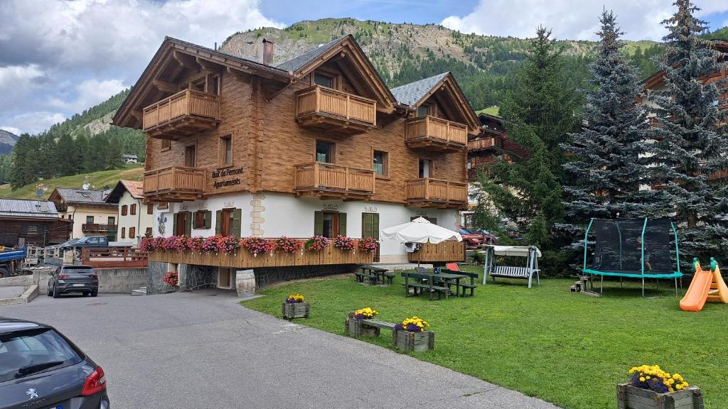 a large wooden house with a playground in front of it at Bait da Pemont in Livigno