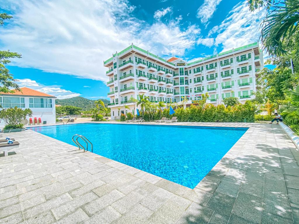 a hotel with a swimming pool in front of a building at Sangkahak Mith Hotel in Kep