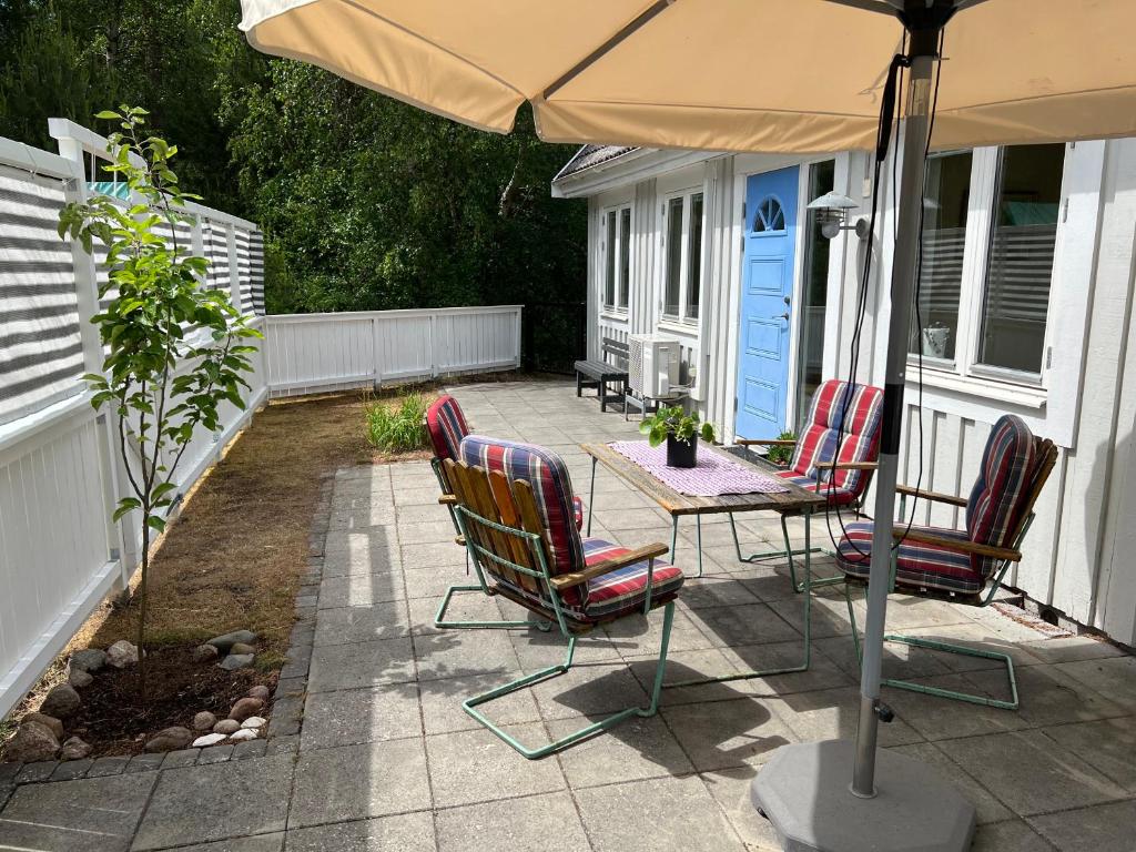 een patio met stoelen en een tafel met een parasol bij Ljunghusen Guesthouse 