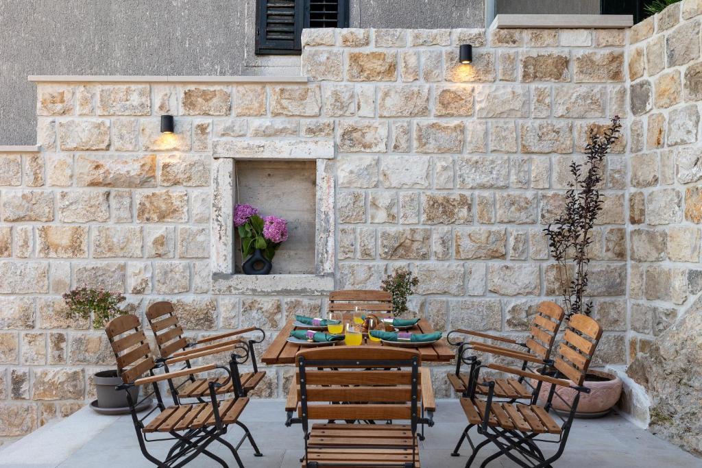 un patio con tavolo, sedie e parete in pietra di Holiday Home Nico's a Cavtat