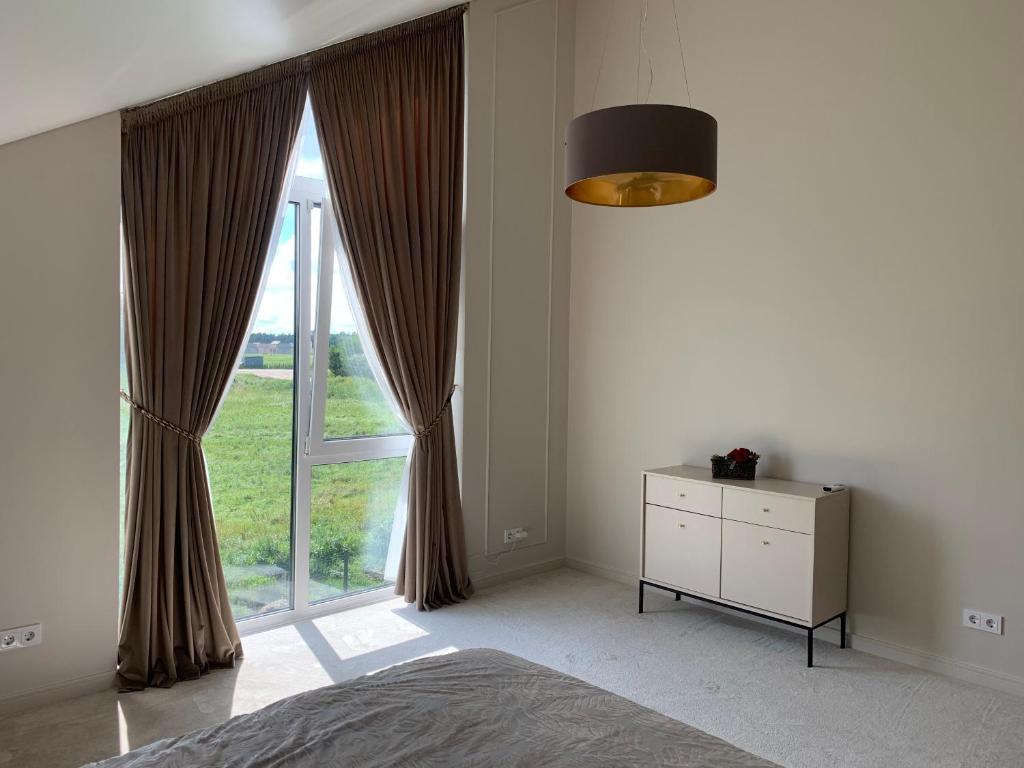 a bedroom with a bed and a large window at Makin' Memories - Apartamentai Monciškėse in Palanga