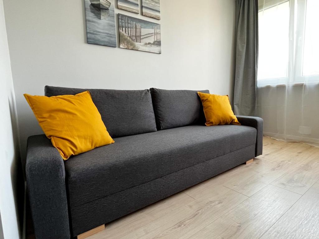 a gray couch with yellow pillows in a living room at Home and Sea in Gdańsk