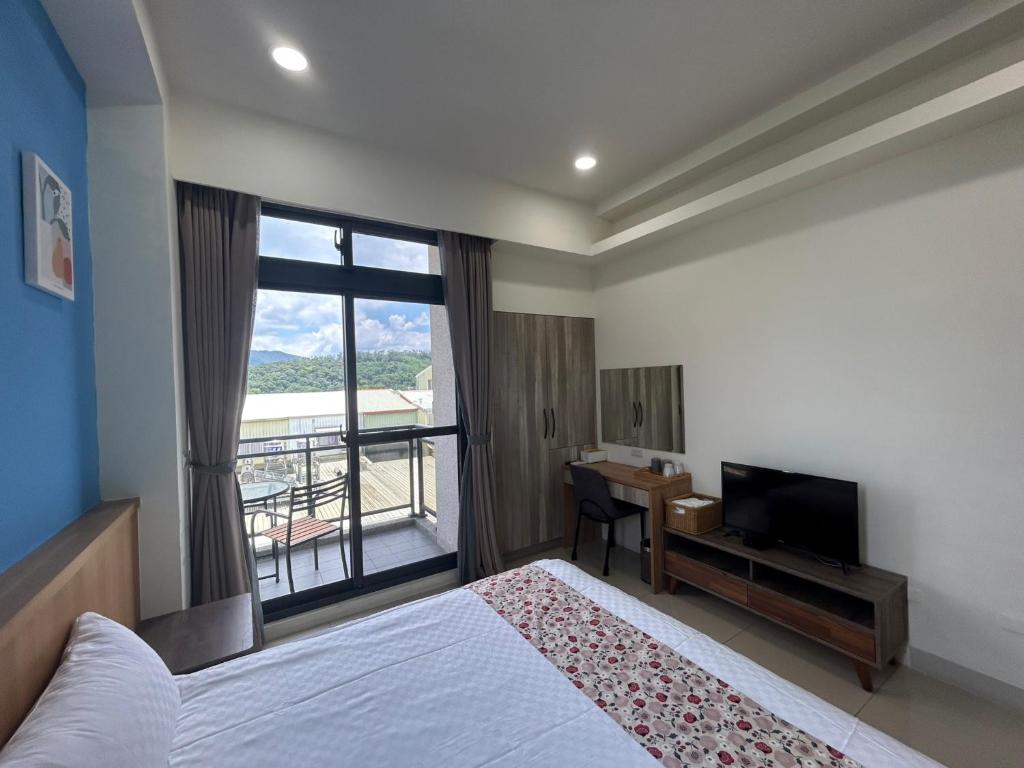Schlafzimmer mit einem Bett, einem Schreibtisch und einem Fenster in der Unterkunft Tung Shiang Homestay in Sanyi