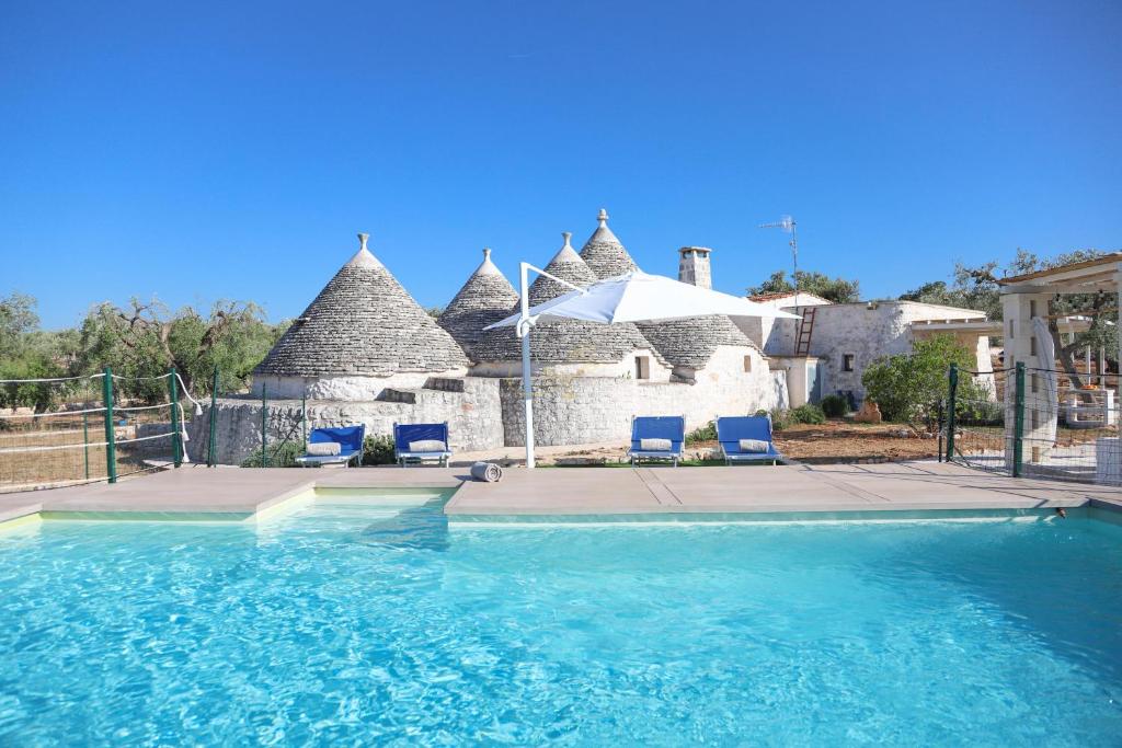 a swimming pool with blue chairs in front of a house at TD Trulli Albapetra Pool Olive Trees in Polignano a Mare