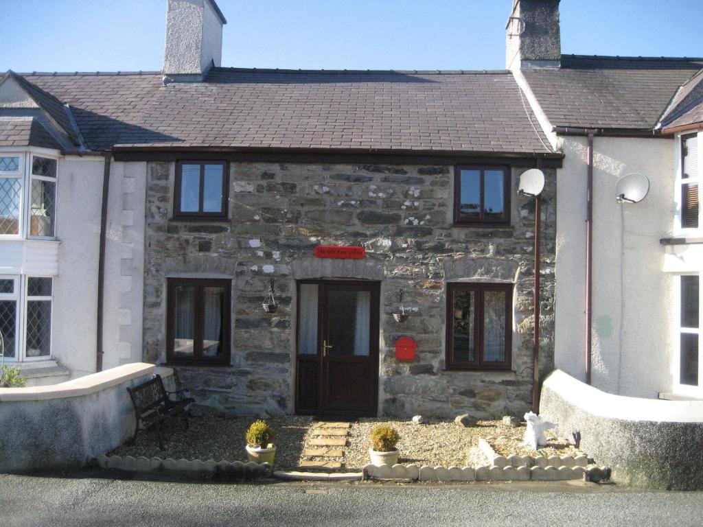 una casa in pietra con una porta nera di The Old Post Office a Cemaes Bay