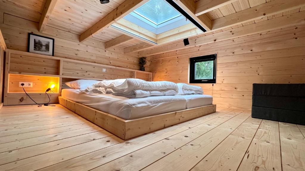 a large bed in a wooden room with a skylight at Tiny House Old Oaks in Hulshorst