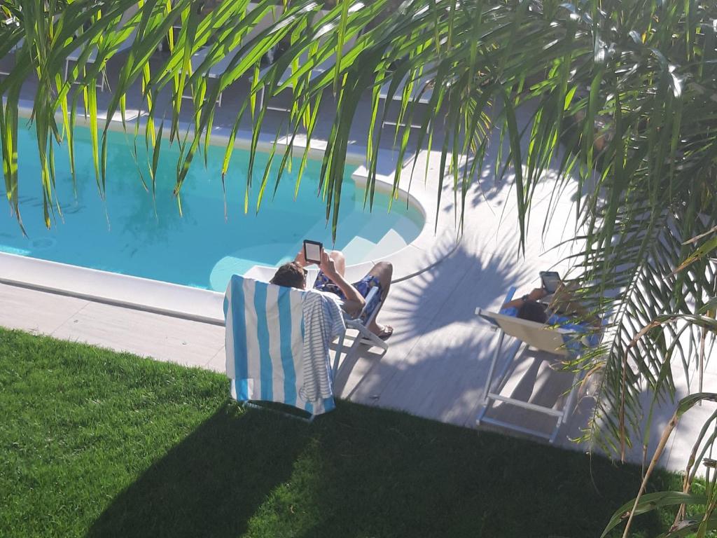 two people sitting in lawn chairs near a swimming pool at LUXURY DREAMS in La Spezia