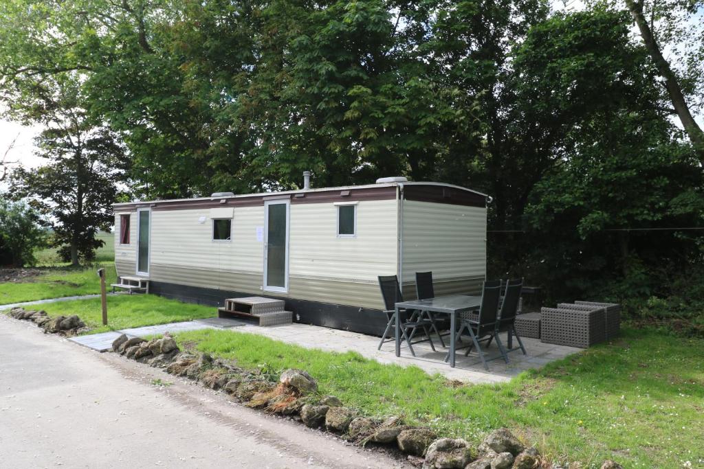 a small white trailer with a table and chairs at De Zuidvliet chalet 1 in Wolphaartsdijk