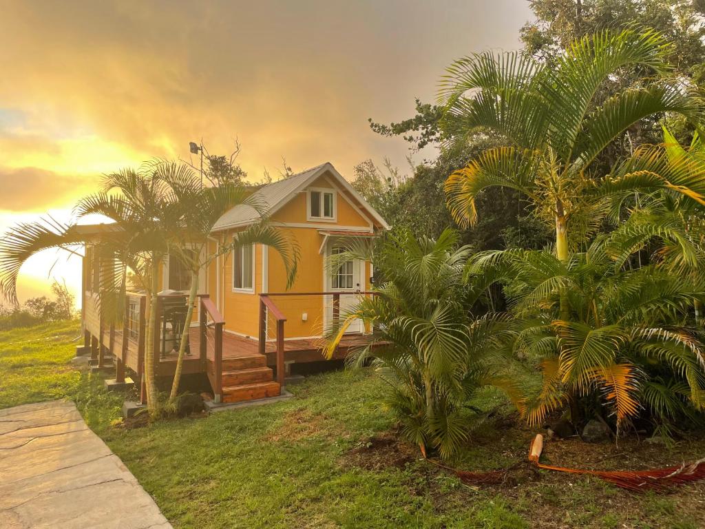 uma pequena casa amarela no meio das árvores em Country Cottage in Papa Bay em Papa Bay Estates