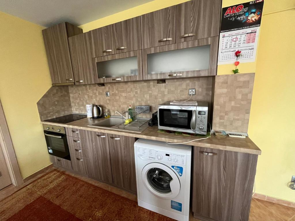 a kitchen with a washing machine and a microwave at Apartment Sanik in Varna City
