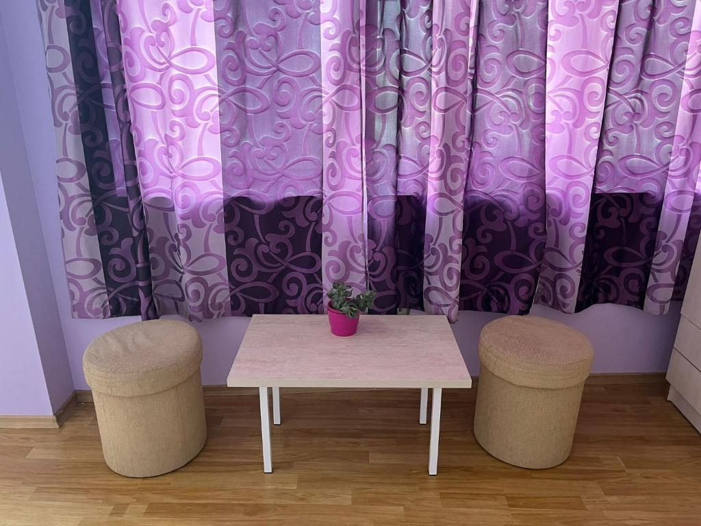 a table and two stools in front of a purple curtain at Apartment Sanik in Varna City