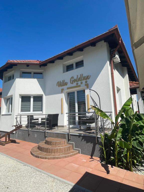 a white building with tables and chairs in front of it at Villa Goldlux in Bihać