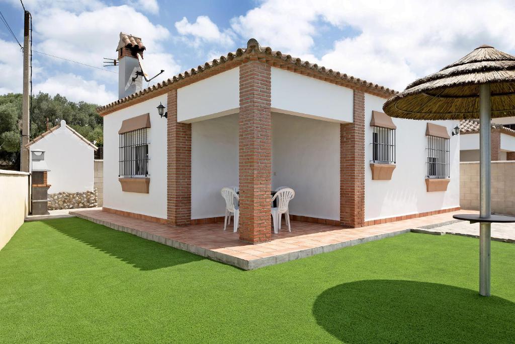 une petite maison avec une pelouse devant elle dans l'établissement Casita Torre de Meca 1 Sin Piscina, à Los Caños de Meca